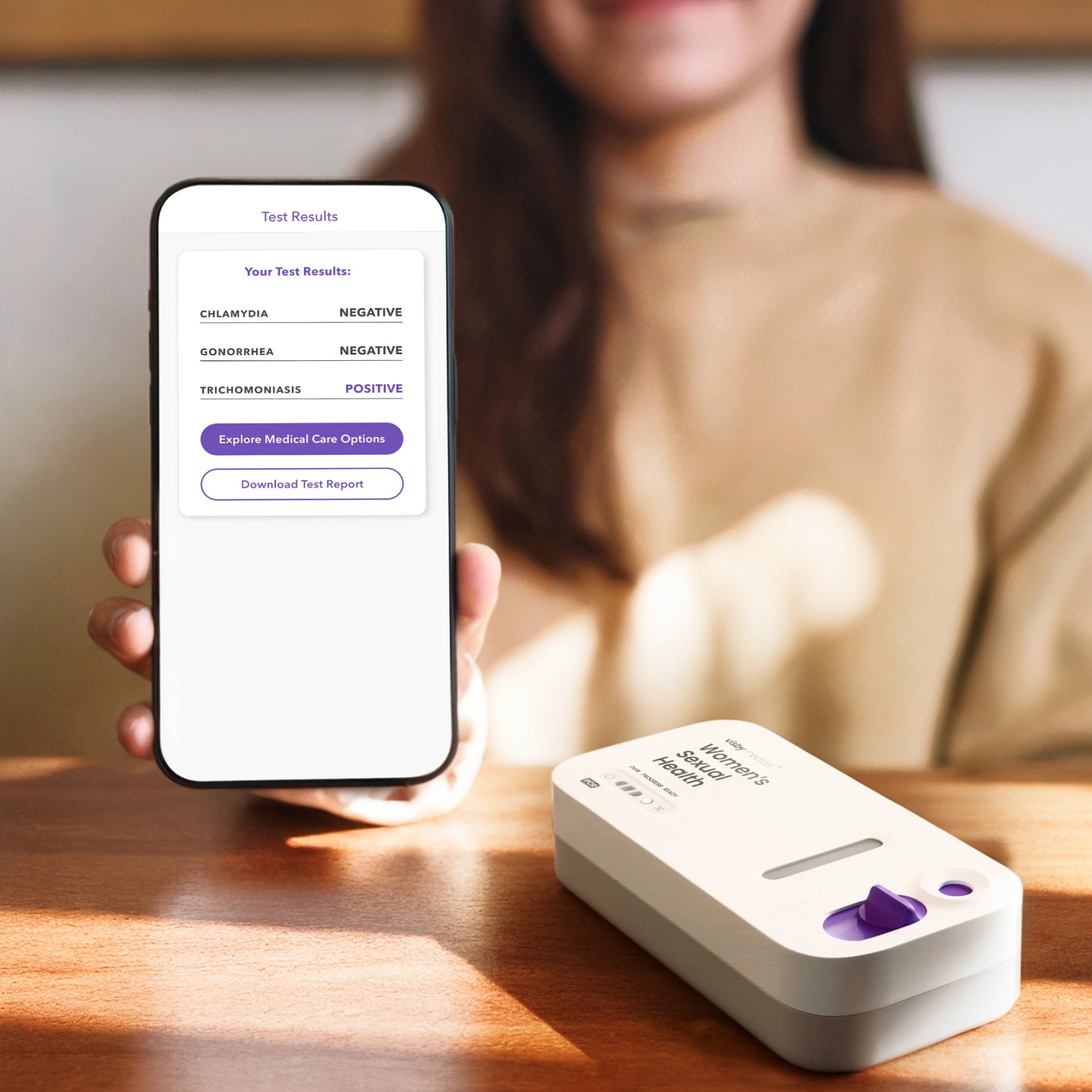Person holding smartphone displaying Visby STI test results with device on table